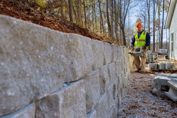 A man constructs a sturdy retaining concrete wall, demonstrating skill and focus in his work on the outdoor project in Pearson, GA.