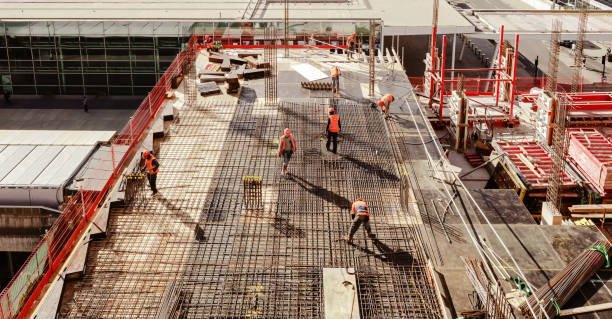 A group of concrete contractors collaborating on a busy construction site, surrounded by machinery and building materials.