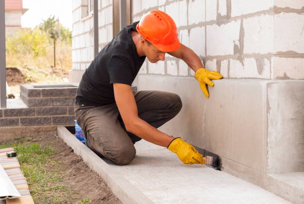 A man applies cement to a wall, focused on his task, showcasing concrete services in Paybestain GA during construction work.