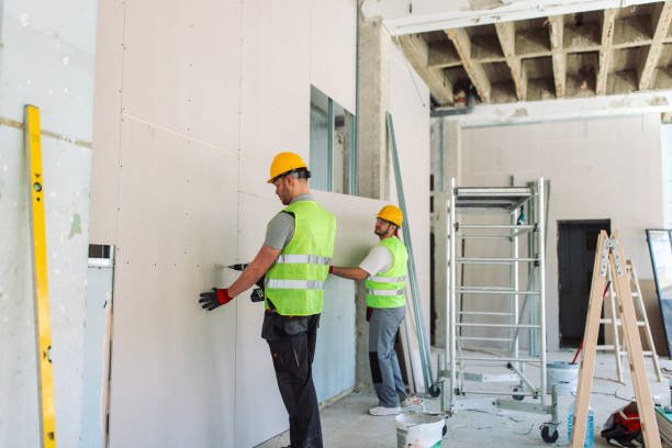 Two men in safety vests are collaborating on a concrete wall installation project, working diligently on constructing a durable wall.