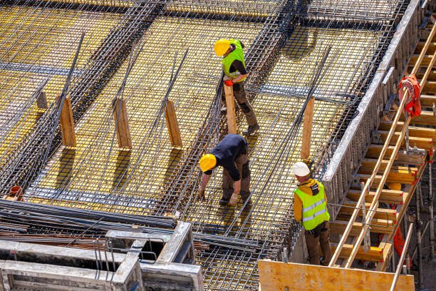 Best concrete contractors in Dallas, GA—construction workers wearing hard hats and safety vests working on a site with machinery and materials.