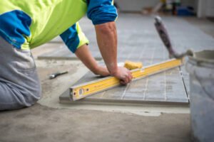 A contractor laying tiles in a geometric pattern, ensuring a precise and durable surface for residential or commercial driveway installation.