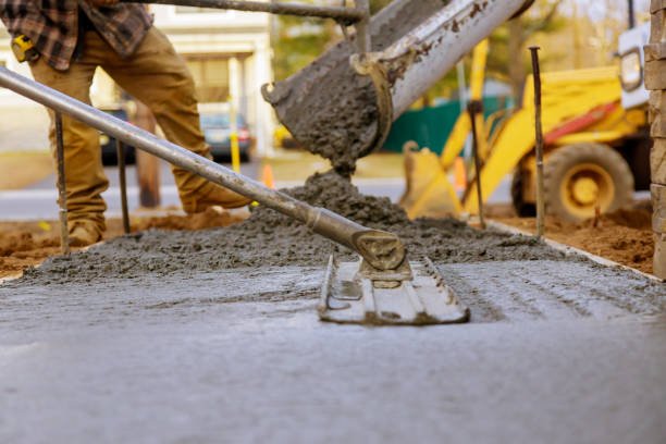 A concrete contractor in Atlanta, GA pours wet concrete onto a newly formed sidewalk, focusing on the task at hand.