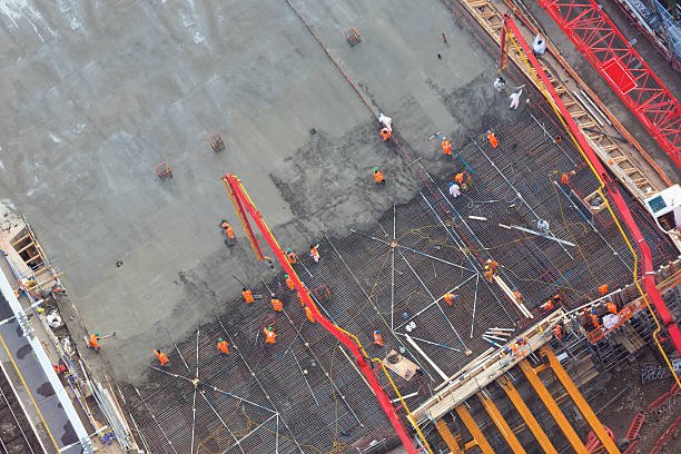 Construction site with workers and machinery actively involved in concrete foundation work for a new building project.