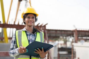 A woman wearing a hard hat and safety vest holds a clipboard at a Metro Atlanta worksite, overseeing custom concrete work.