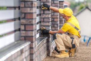 A concrete contractor in Atlanta, GA repairing a residential brick wall using professional tools.