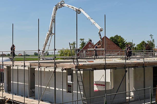 A crane is positioned on top of a concrete roof slab of a building under construction.