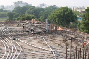 A construction site featuring steel pipes, wires, and a concrete roof slab under development.