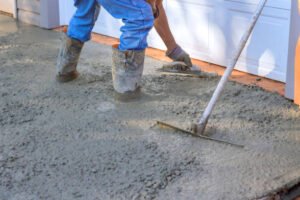 A man actively pouring concrete to create a sidewalk, representing concrete services in Mableton, GA.
