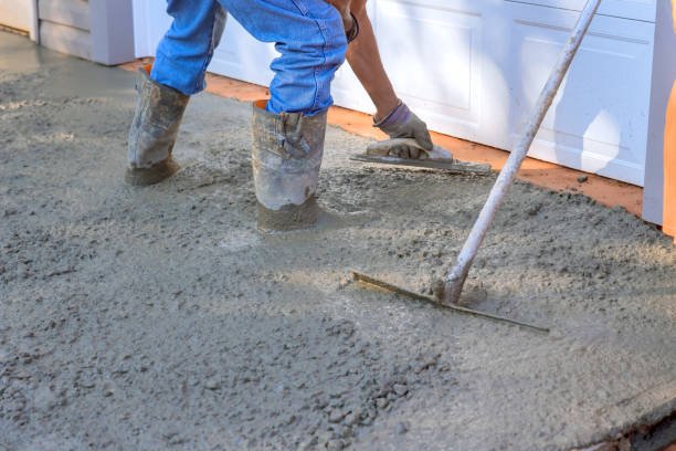 A man actively pouring concrete to create a sidewalk, representing concrete services in Mableton, GA.