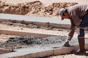 A concrete contractor shapes a slab, preparing it for a driveway, showcasing skills in construction and design.