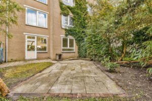An apartment featuring a lush garden and a charming brick path leading through a well-maintained outdoor space.