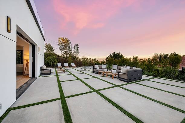 A backyard concrete patio surrounded by lush grass, featuring a smooth concrete surface for outdoor relaxation and gatherings.