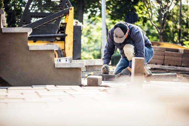 A man works diligently on a brick patio, laying concrete for a well-structured outdoor installation.
