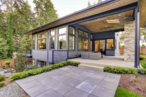 A modern home featuring a custom patio design and a stone walkway leading to the entrance.