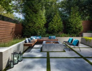 A modern backyard featuring concrete seating and a fire pit, showcasing a stylish patio design for outdoor gatherings.