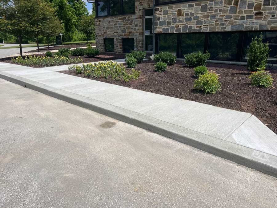 Commercial concrete walkway with landscaping in front of a commercial building, providing a welcoming entrance for pedestrians.