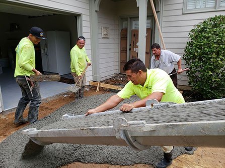 concrete services, workers are pouring concrete in the driveway of a house